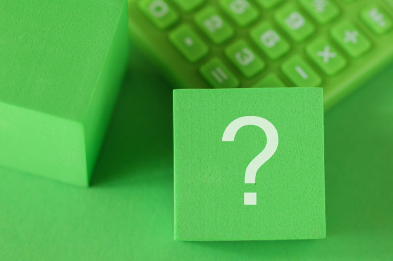 Question mark sign on block cube, green calculator on green background. ESG support concept